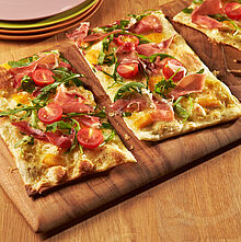 Frisch aus dem Ofen: Herzhafter Flammkuchen mit Rucola und Schinken.