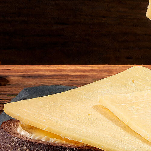 Cheddar am Stück - Mindestens 12 gereifter Cheddar Käse in Scheiben drapiert auf einer Schieferplatte