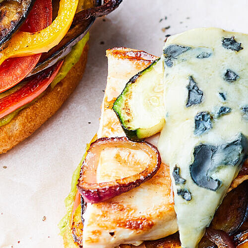 Saftiger Grill-Hähnchen-Burger mit geschmolzenem Blauschimmelkäse auf einem knusprigen Brötchen